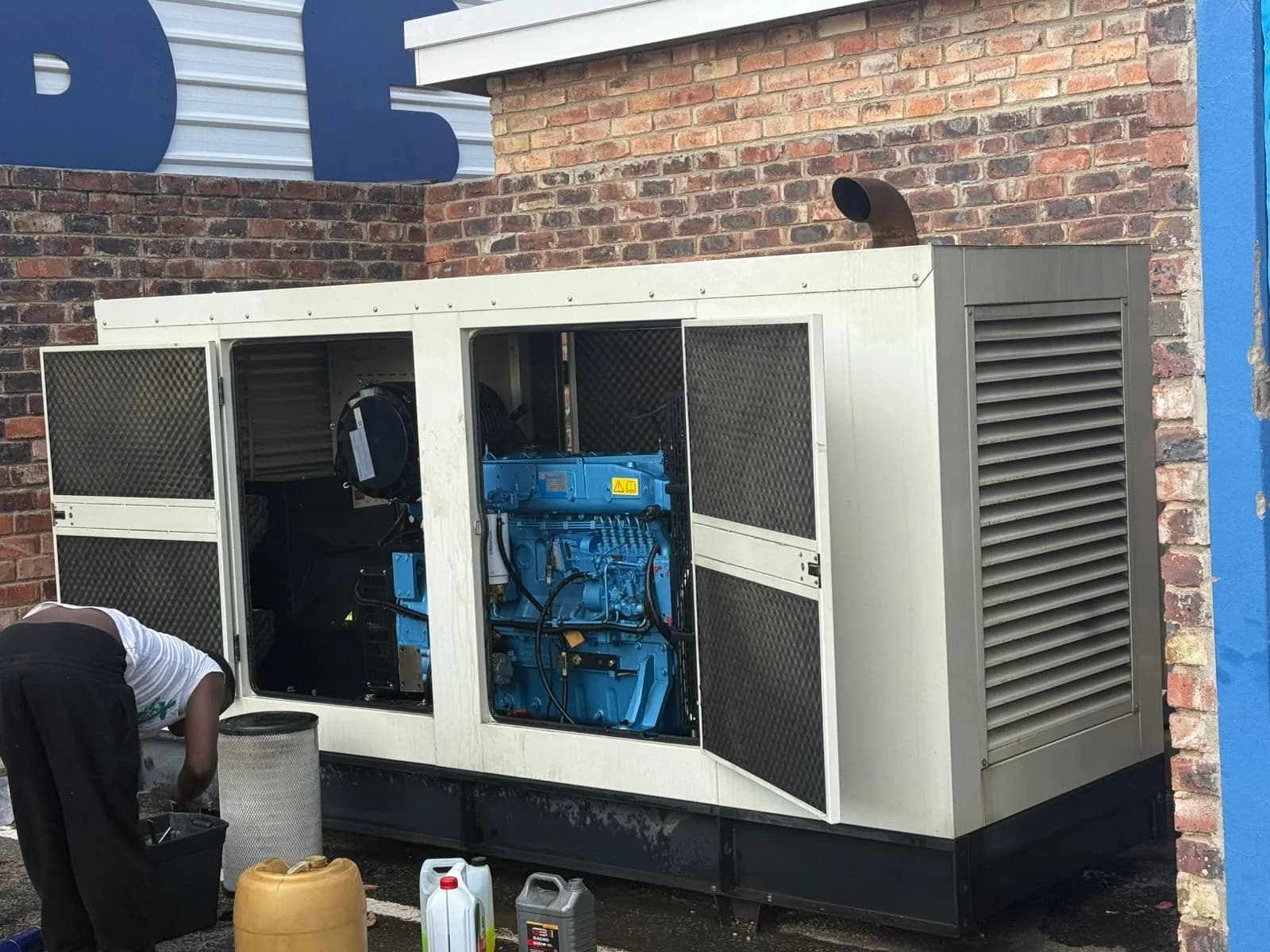 Two technicians inspecting a standby generator controller, battery and coolant