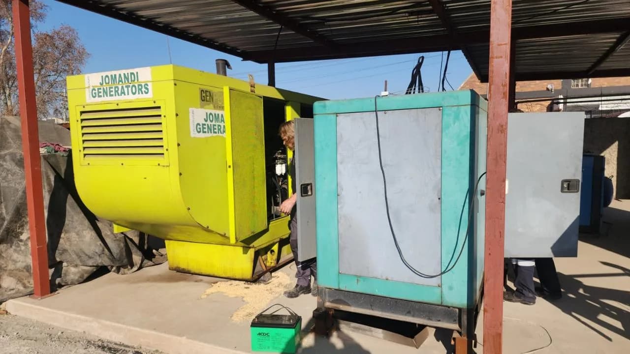 Two technicians inspecting a large diesel generator for an inner-city standby installation