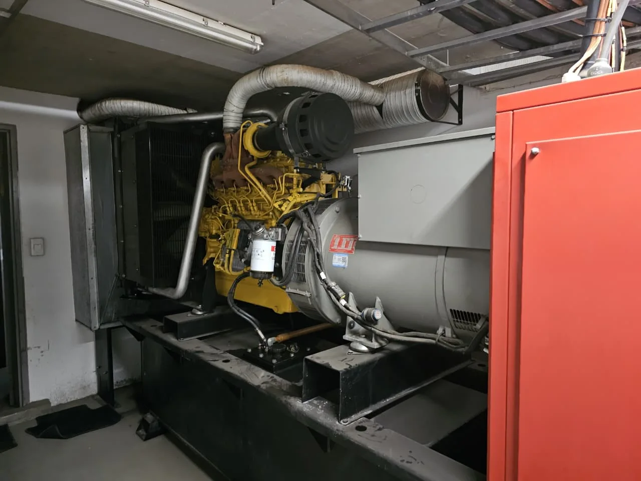 Two technicians inspecting a standby diesel generator during a service visit