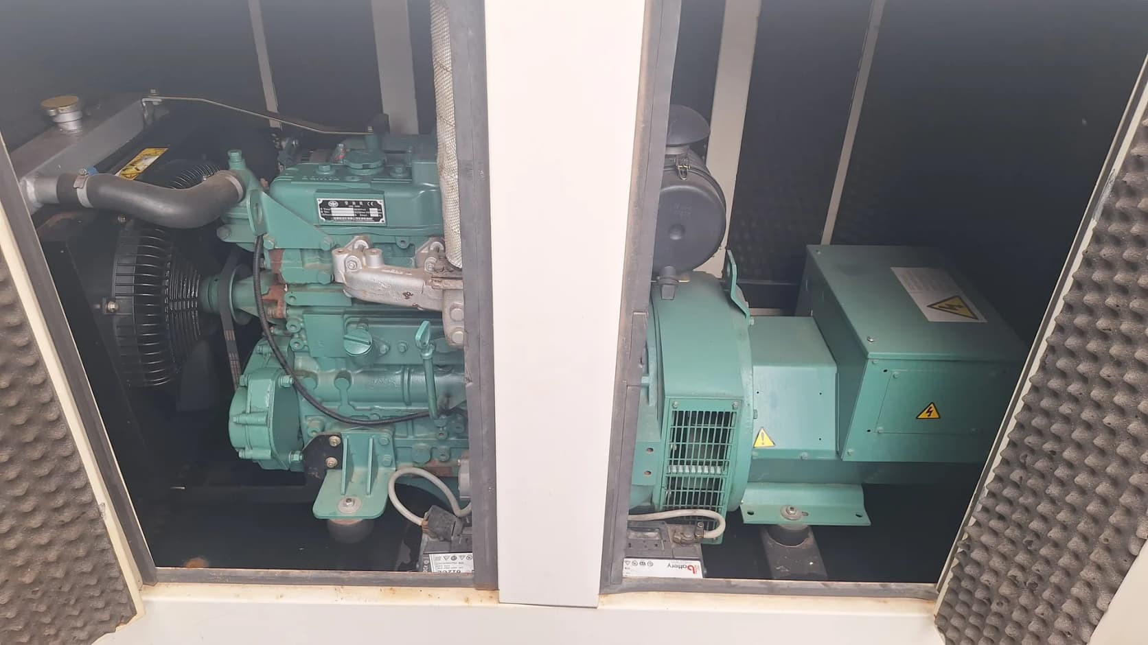 Canopy doors open on a green diesel engine and matching alternator, with acoustic foam on the doors