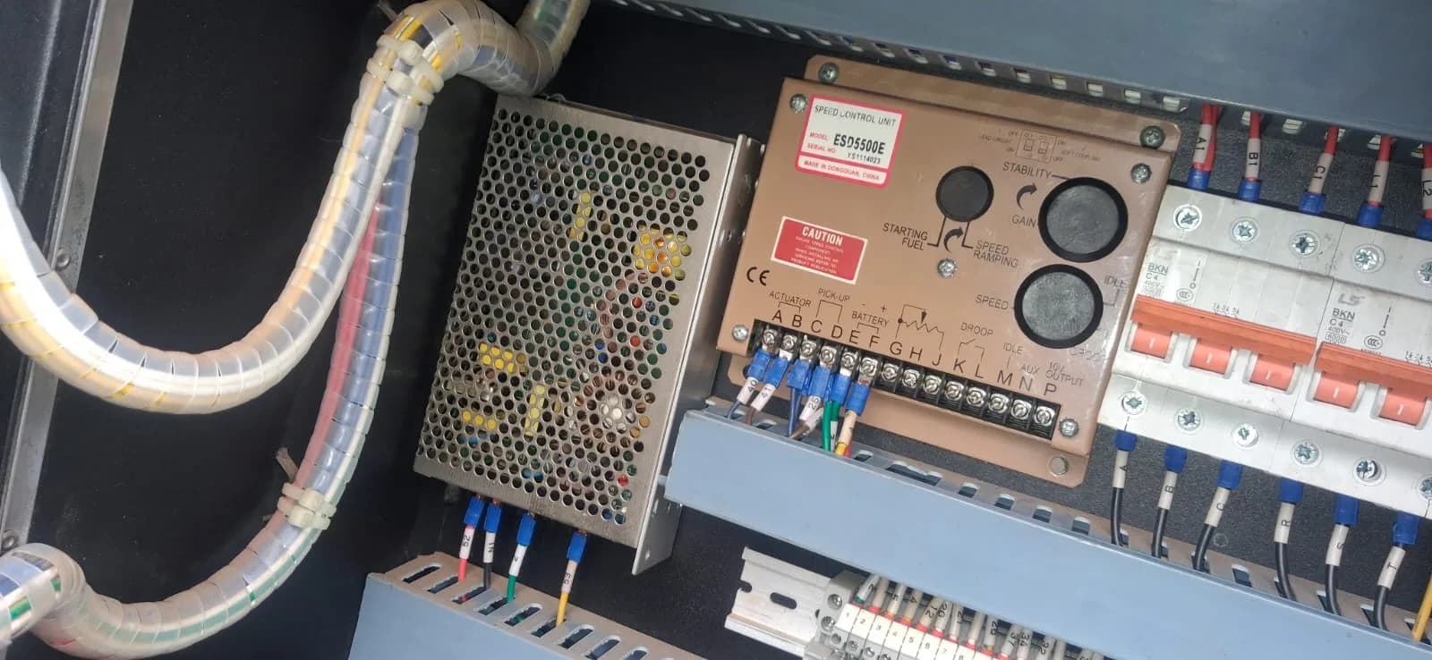 Inside a generator control panel: ESD5500E speed control unit, power supply, breakers and labelled terminal wiring