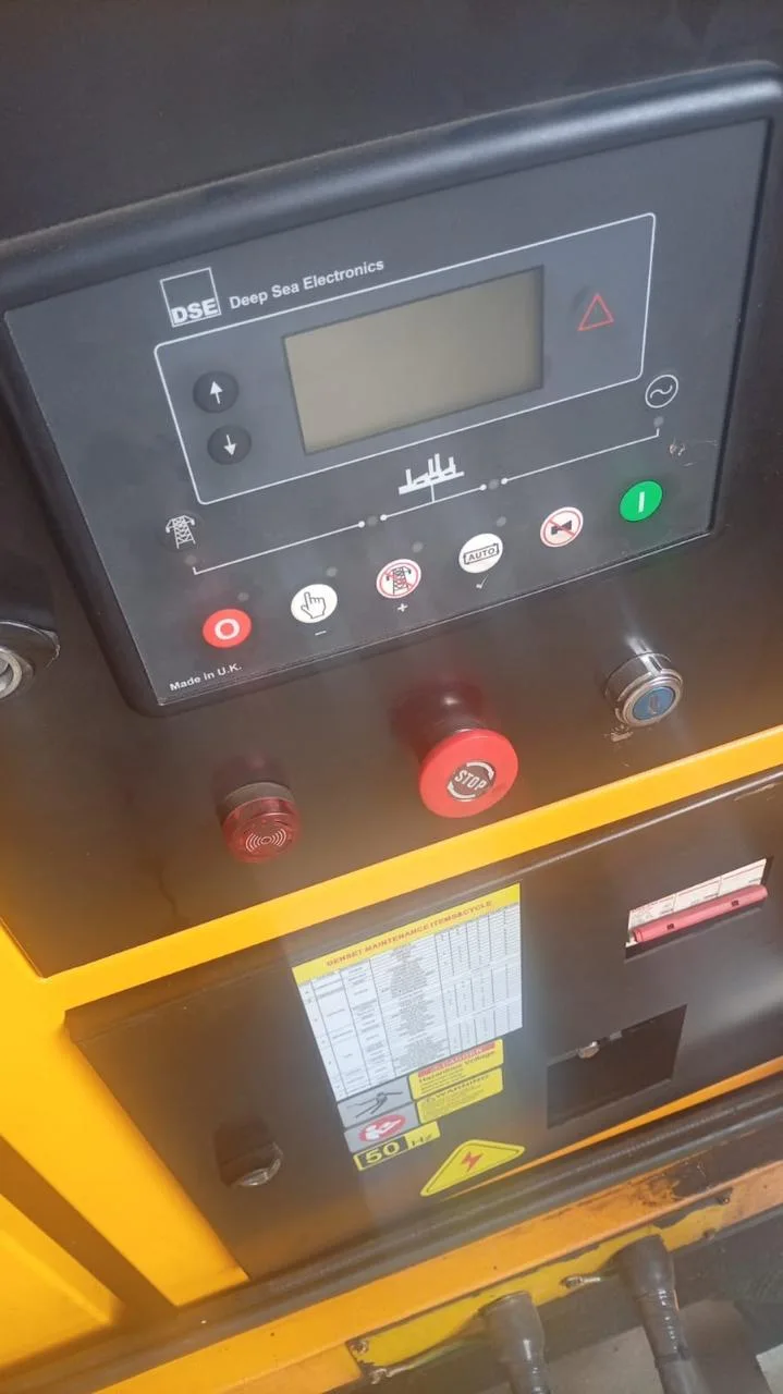 Deep Sea Electronics controller with emergency stop button above a wiring diagram label in a yellow canopy