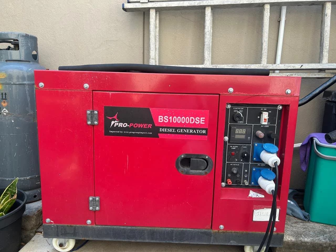 Two technicians servicing a standby generator on site, with a larger set behind