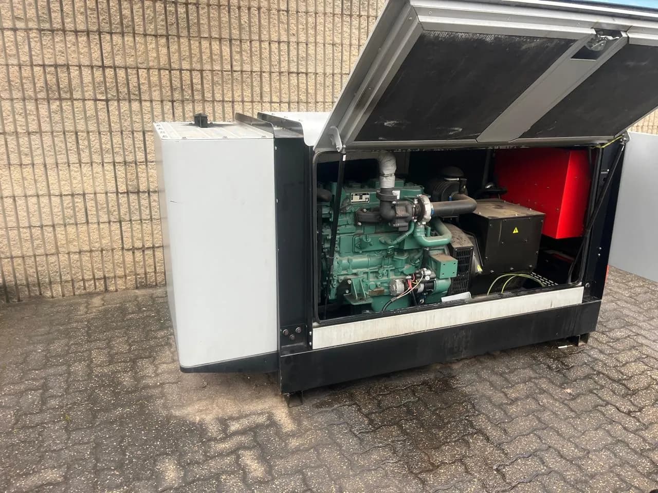 Diesel generator with the canopy raised, showing the engine and alternator